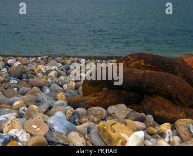 Chain anchor on beech to hold fishing vessels pulled up high on the shingle beach at Aldeburgh in Suffolk England Stock Photo