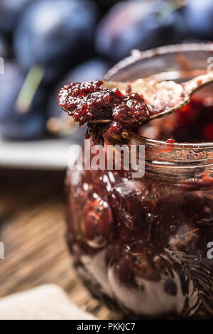 Close-up spoon from plum jam and fresh plums in the background. Stock Photo