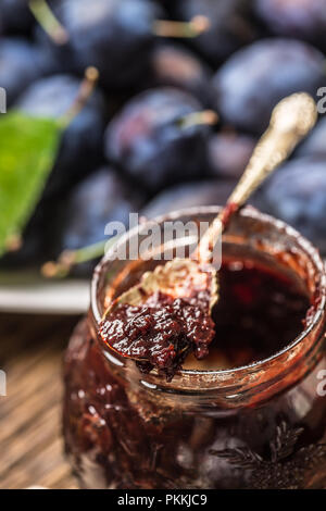 Close-up spoon from plum jam and fresh plums in the background. Stock Photo