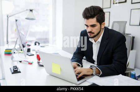Young handsome architect working on laptop in office Stock Photo