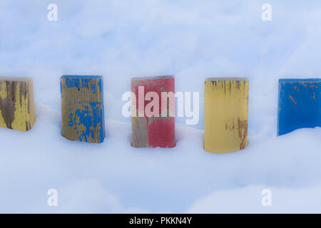 Textured Colorful Painted Blue, Red, Yellow Wooden Picket Fence Planks In Deep Snow, Colorful Rustic Style Background For Vintage Winter Season Wallpa Stock Photo