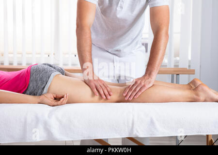 Relaxed Young Female Patient Receiving Massage By Therapist In Clinic Stock Photo