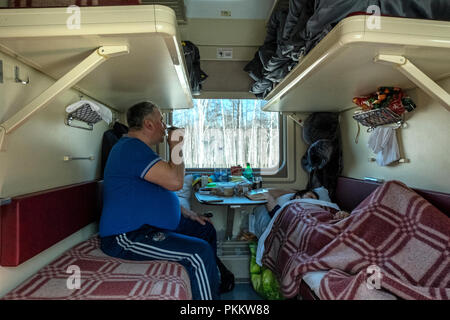 SIBERIA, RUSSIA - MARCH 20, 2018: The Russian passenger is drinking tea when his wife is sleeping in Trans Siberian Express,  Novosibirsk , Russia. Stock Photo