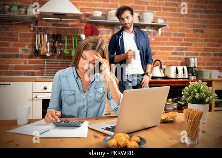 Young couple in savings and home budget concept. Managing finances, taxes using calculator and laptop. Stock Photo