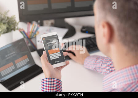 Designer working on responsive web design project. Web developer and programmer working in office with modern devices on desk Stock Photo
