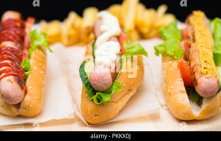 Three assorted hot dogs with frankfurter sausages topped with different dressings namely mayonnaise, tomato ketchup and mustard Stock Photo