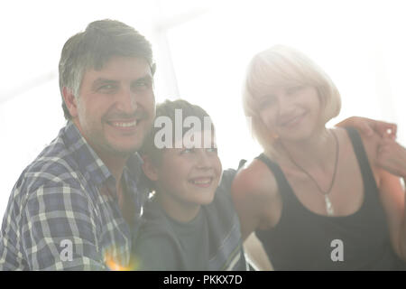 Parents and their son sit huddled in the living room and smiling Stock Photo