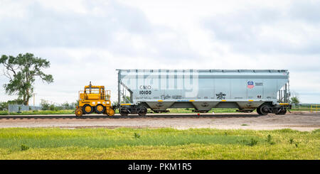 Ovid, CO, USA - May 28, 2018: Union Pacific covered hopper grain railcar with a mobile car mover (Trackmoblie 95TM) in rural eastern Colorado. Stock Photo