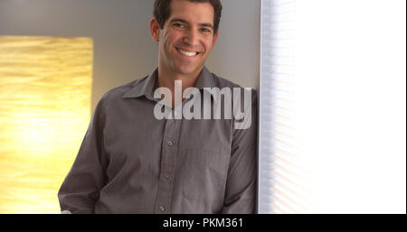 Casual businessman smiling and staring out window Stock Photo