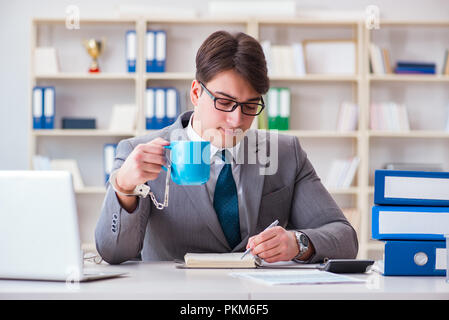 Businessman chained with handcuffs to his coffee Stock Photo