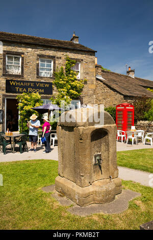 UK, Yorkshire, Wharfedale, Burnsall, old red phone box, tea room and water supply on village green Stock Photo