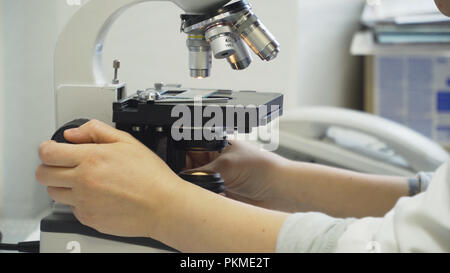 Doctor woman working with a microscope in Laboratory. Female scientist looking through a microscope in lab. Scientist using a microscope in a laboratory. Stock Photo