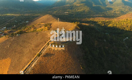 The sign of the city of Coron is on a hill, a famous tourist place. Aerial view: Catholic cross on a hill, mountain in the town of Coron, Philippines,Palawan Busuanga. Travel concept. Stock Photo