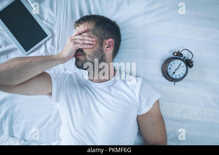 Tired man sleeping on bed after using his digital tablet Stock Photo
