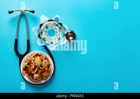 studio shoot Chinese herb medicine and pills wrapped with a stethoscope on blue background with copy space Stock Photo