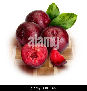 Appetizing and healthy red plums, whole and cut into segments with an aspect of illustration. Includes leaves of the plum tree. Isolated on white back Stock Photo