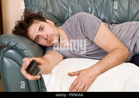 A young man watches television and changes channels while relaxing Stock Photo