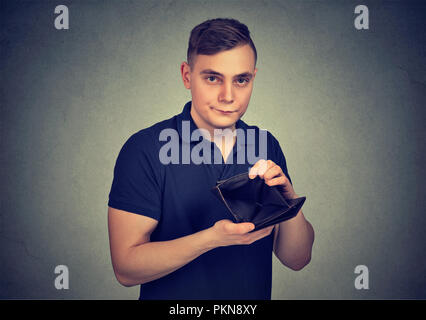 Young man showing empty wallet having no money and looking upset at camera Stock Photo