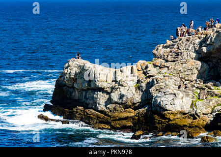 People whale watching from rocks in Hermanus, South Africa Stock Photo