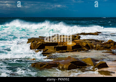 Small waves crashing on brown rocks in the South Atlantic, South Africa Stock Photo