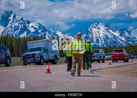 YELLOWSTONE, MONTANA, USA MAY 24, 2018: Outdoor view of cars parked at one side of the road with crowd of people at Yellowstone Grand Teton National Park, Wyoming Stock Photo