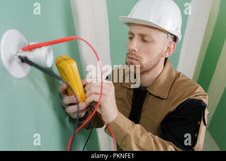 electrician checking socket voltage with digital multimeter Stock Photo