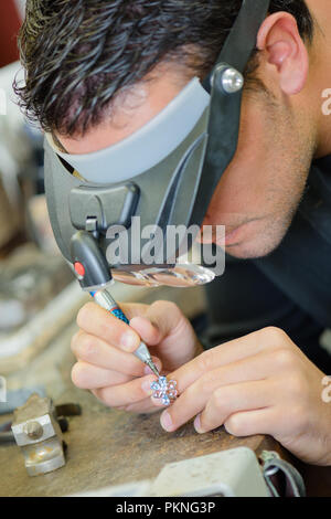 jeweler soldering a ringlooking through magnifying mask Stock Photo