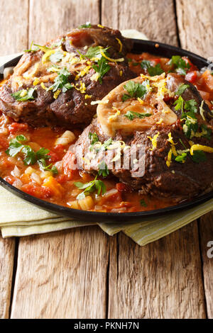 Italian veal steak Ossobuco alla milanese with spicy sauce close-up on the table. vertical Stock Photo