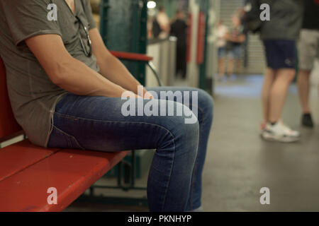 closeup of a young caucasian man wearing casual clothes sitting in a bench in an underground station Stock Photo