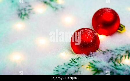 Two red christmas balls with fir branches and lights in the snowsymbol Stock Photo