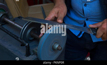 Man grinding on abrasive cutting and knife-sharpening stones Stock Photo