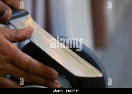 Man grinding on abrasive cutting and knife-sharpening stones Stock Photo