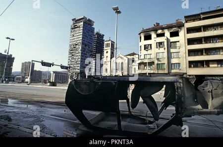 15th March 1993 During the Siege of Sarajevo: the shell of a small burned-out car lies upside down on tramlines on Sniper Alley. Stock Photo