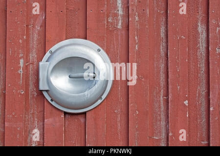 Metal lid for garbage throw on wood background painted in Falu red color traditional paint in Sweden Stock Photo