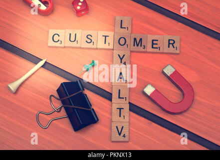 Customer Loyalty theme with smart phone on wooden table. Stock Photo
