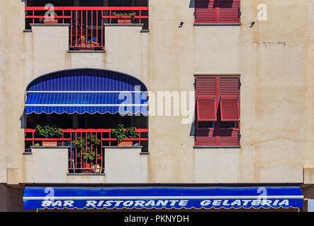 Facade of an old building in Ventimiglia in Liguria region of Italy with a restaurant bar and gelateria advertisement on an awning Stock Photo