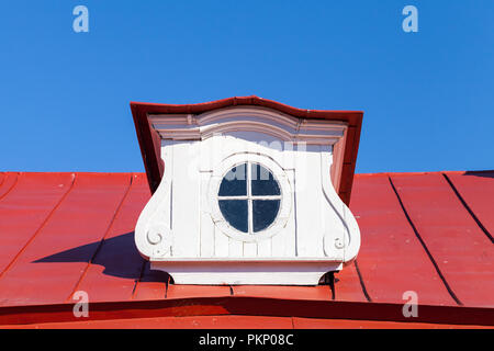 Vintage attic window on red roof slope in decorative white wooden frame Stock Photo