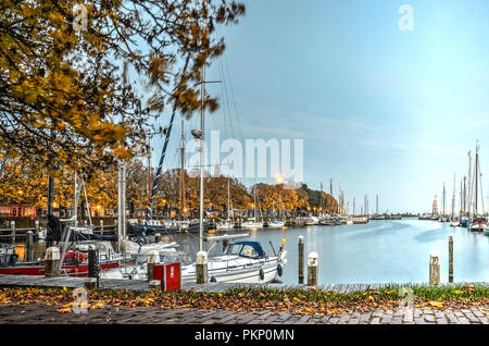 Enkhuizen, The Netherlands, October 26, 2015: Moon rising, not long after sunset, over the marina in the Outer Harbour, lined with trees in autumn col Stock Photo