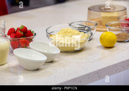 Ingredients for cooking strawberry pie or cake on white background. Side view. Flour, milk, sugar, strawberry, lemon. Bakery background. Recipe for strawberry pie. Stock Photo