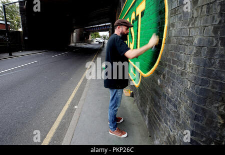 Artist Lionel Stanhope working underneath a railway bridge adjacent to Selhurst railway station, south London, the street artist is transforming some of Londons railway bridges into works of art. Stock Photo