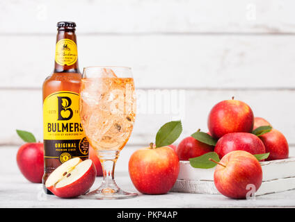 LONDON, UK - SEPTEMBER 13, 2018: Bottle of Bulmers Original Cider and glass of ice cubes with fresh apples on wood background. Stock Photo