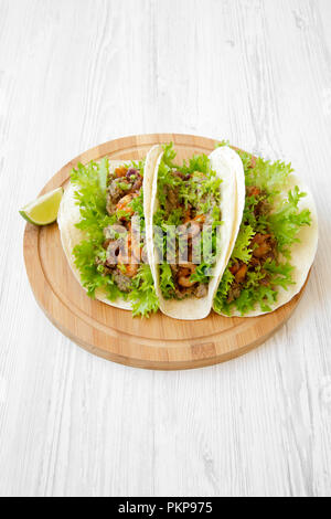 Shrimp tacos on round bamboo board on white wooden background, high angle view. Mexican cuisine. Stock Photo