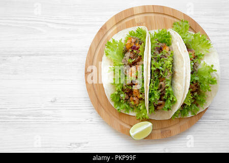 Shrimp tacos on round bamboo board on white wooden table, top view. Mexican food. Flat lay, overhead, from above. Copy space. Stock Photo