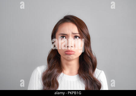 young beautiful sad woman serious and concerned looking worried and thoughtful facial expression feeling depressed isolated grey background in sadness Stock Photo