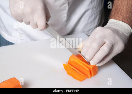 the chef in gloves cuts carrots Stock Photo