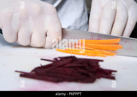 the cook cuts carrots into slices in the restaurant kitchen Stock Photo