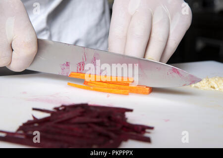 the cook cuts carrots into slices in the restaurant kitchen Stock Photo