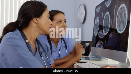 Two doctors reviewing brain scans on hospital computers Stock Photo