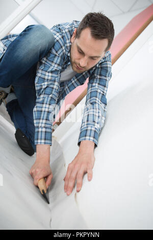 young handyman installing linoleum Stock Photo