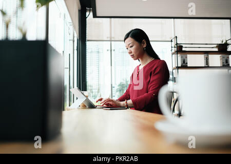 Portrait of happy Chinese female manager working in a bar outside the office. Successful Asian businesswoman smiling Stock Photo